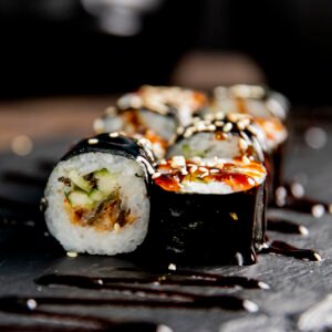 maki roll with cucumber served with sauce and sesame seeds